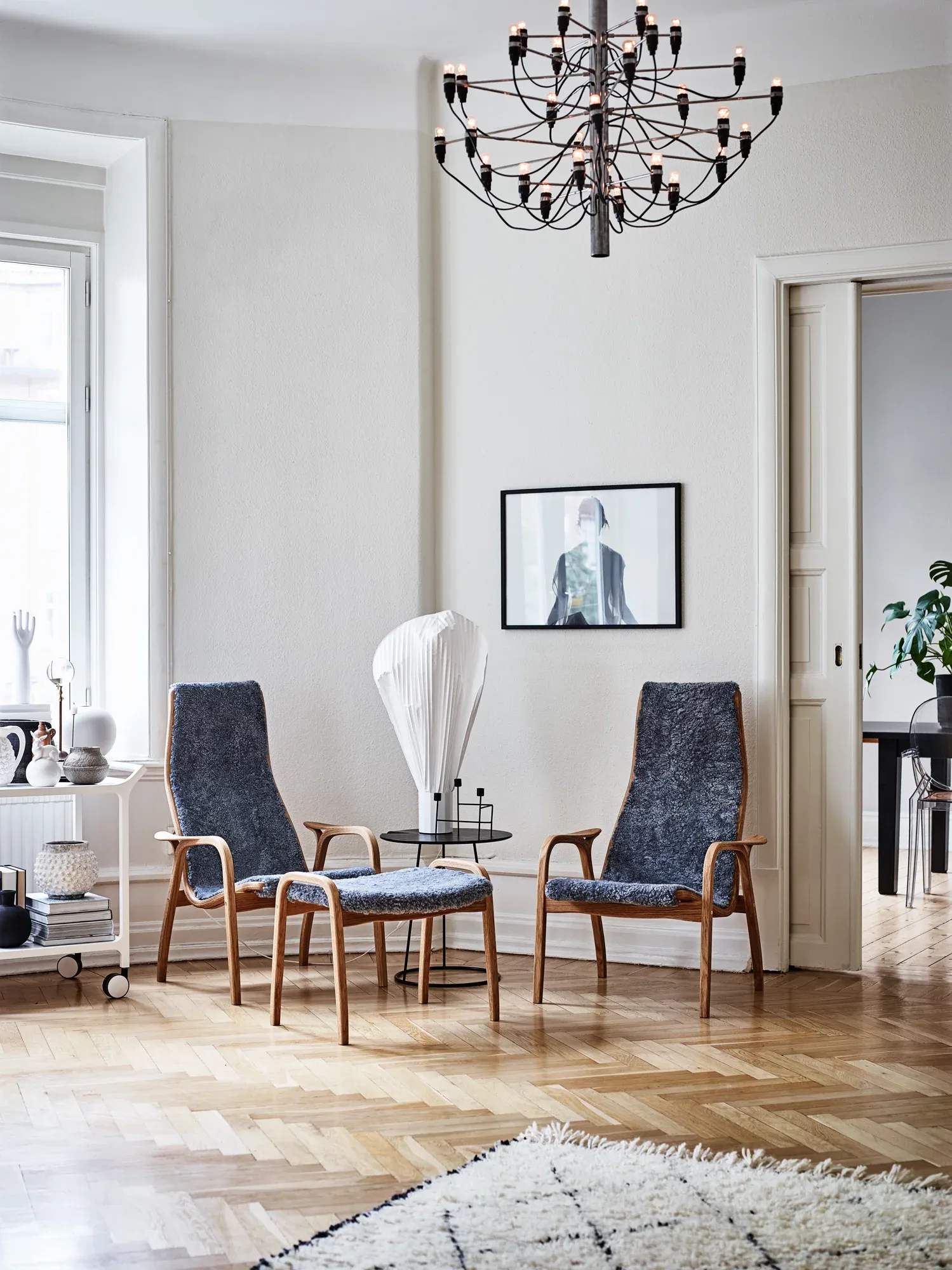 Twee Swedese fauteuils en een voetenbank met houten frames en donkerblauwe bekleding in lichte woonkamer.