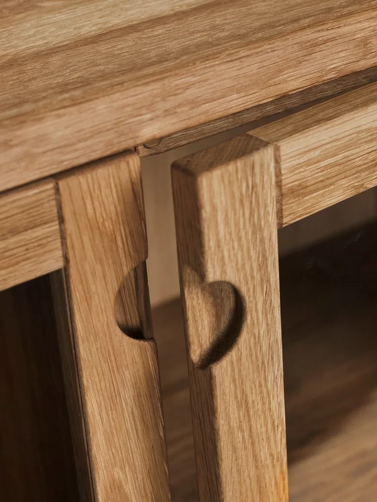 Twee lichte houten panelen, elk met een hartvormige uitsparing, op een meubelstuk.