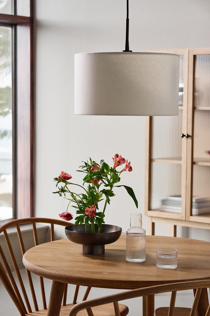 Hier zie je de Soft hanglamp van Belid boven een houten eettafel hangen. 