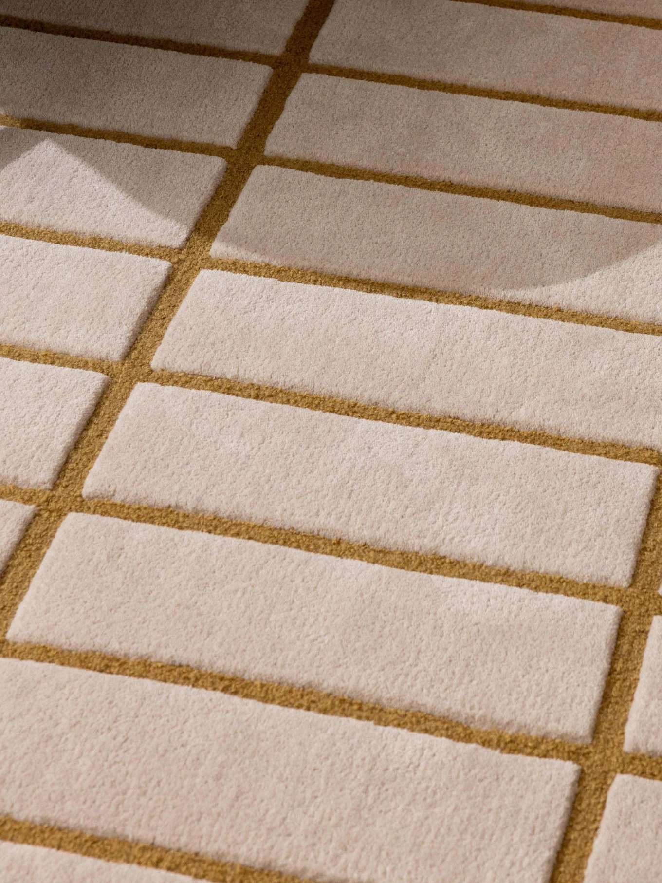 Beige en goudbruin patroon vloerkleed, groene fauteuilpoot en een dienblad met witte theepot en kop.