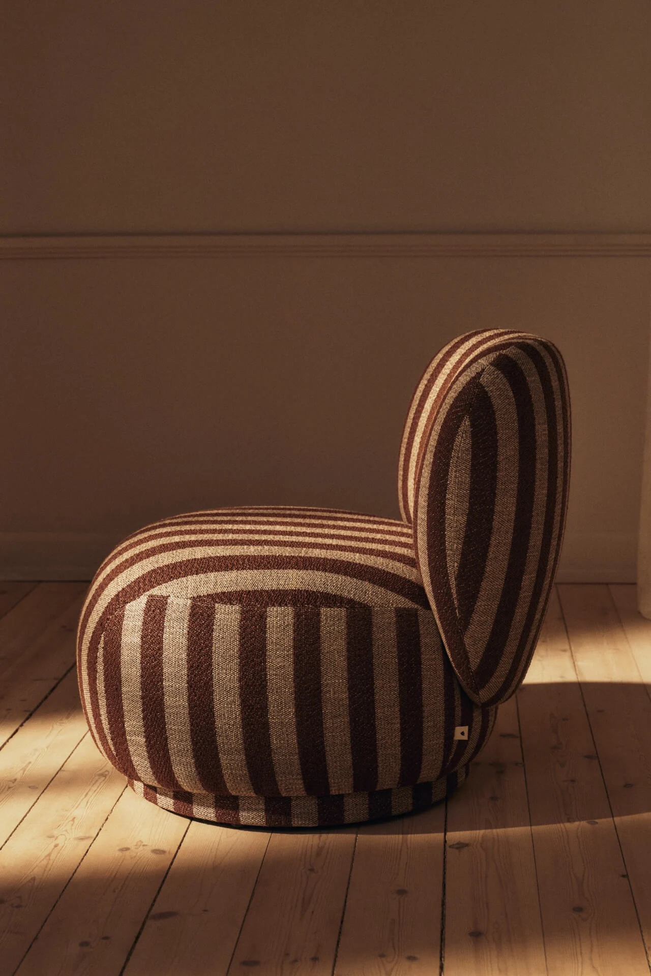 Ronde fauteuil met bruine en beige strepen op een houten vloer.