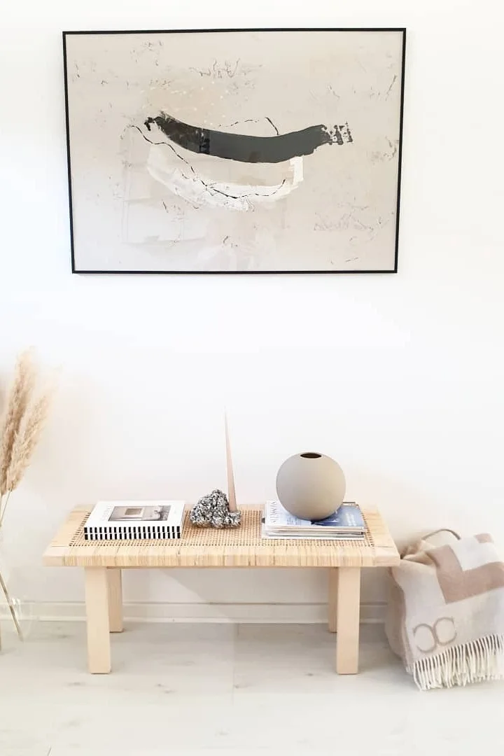 Japandi: Hier zie je een bank versierd met de Ball vaas van Cooee Design, daarnaast een deken van Classic Collection en een foto erboven.