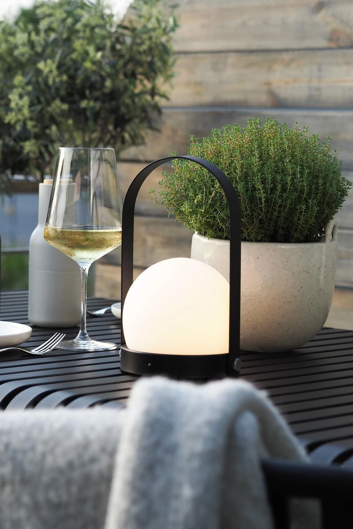 De draagbare Carrie lamp van Audo Copenhagen en de Speckle bloempot van Ferm Living staan op de Palissade tafel van HAY op het terras van @wohngluecksieben.