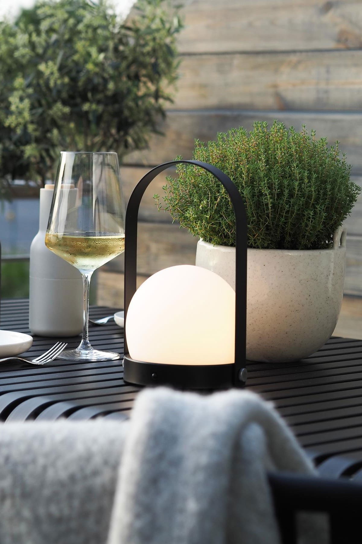 De draagbare Carrie lamp van Audo Copenhagen en de Speckle bloempot van Ferm Living staan op de Palissade tafel van HAY op het terras van @wohngluecksieben.