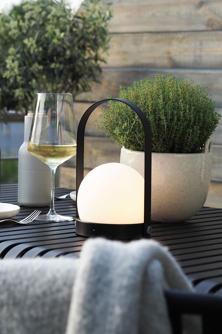 De draagbare Carrie lamp van Audo Copenhagen en de Speckle bloempot van Ferm Living staan op de Palissade tafel van HAY op het terras van @wohngluecksieben.