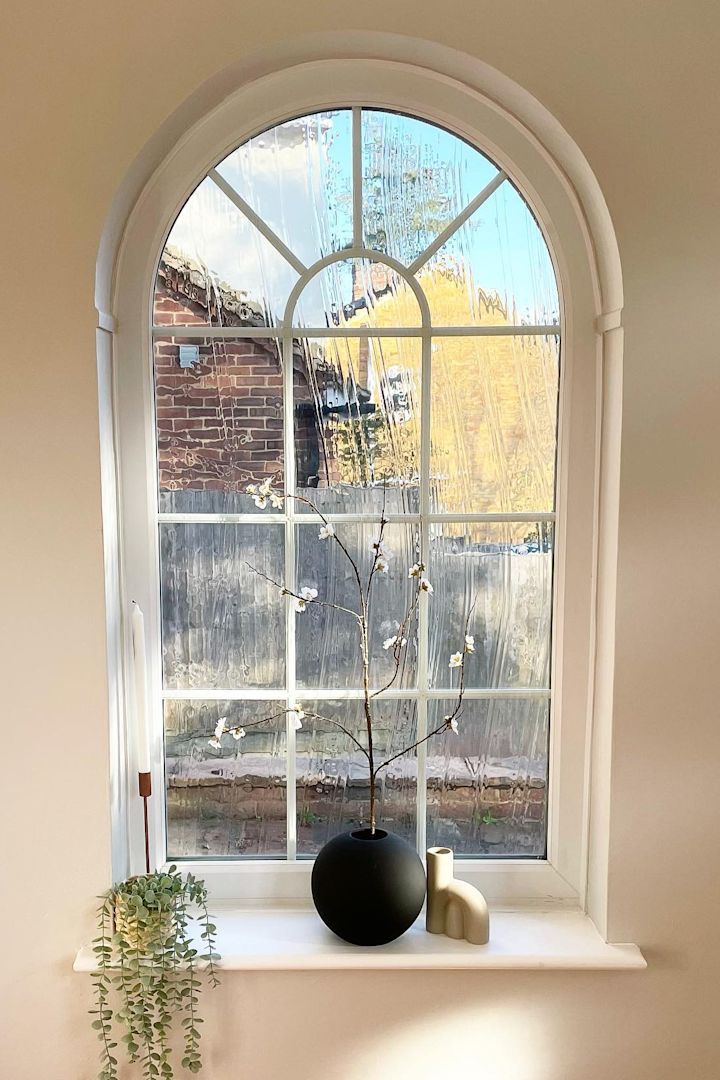 Hier zie je het mooie boograam met vensterbank van @abrysonhouse, dat is versierd met kandelaars en de zwarte bolvaas van Cooee Design met lentebloemen.