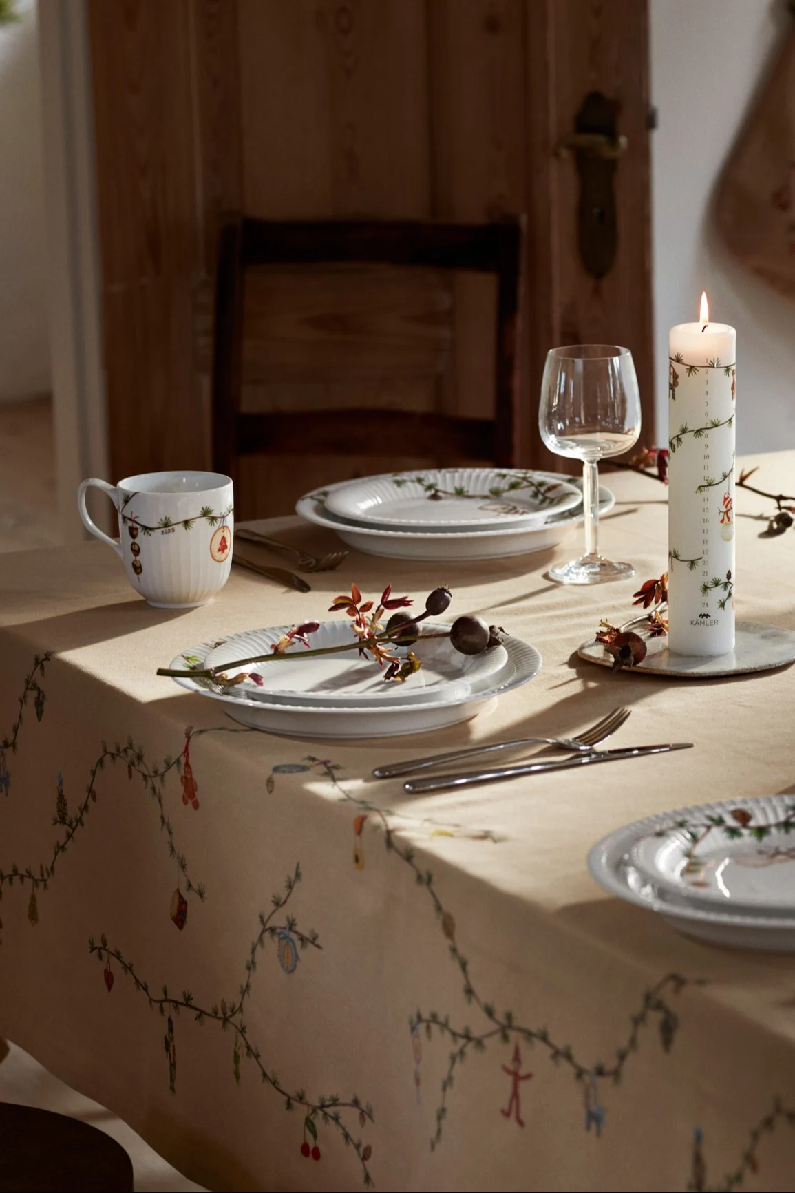 Een kersttafel gedekt met kerstservies en het Hammershøi-tafelkleed van Kähler.