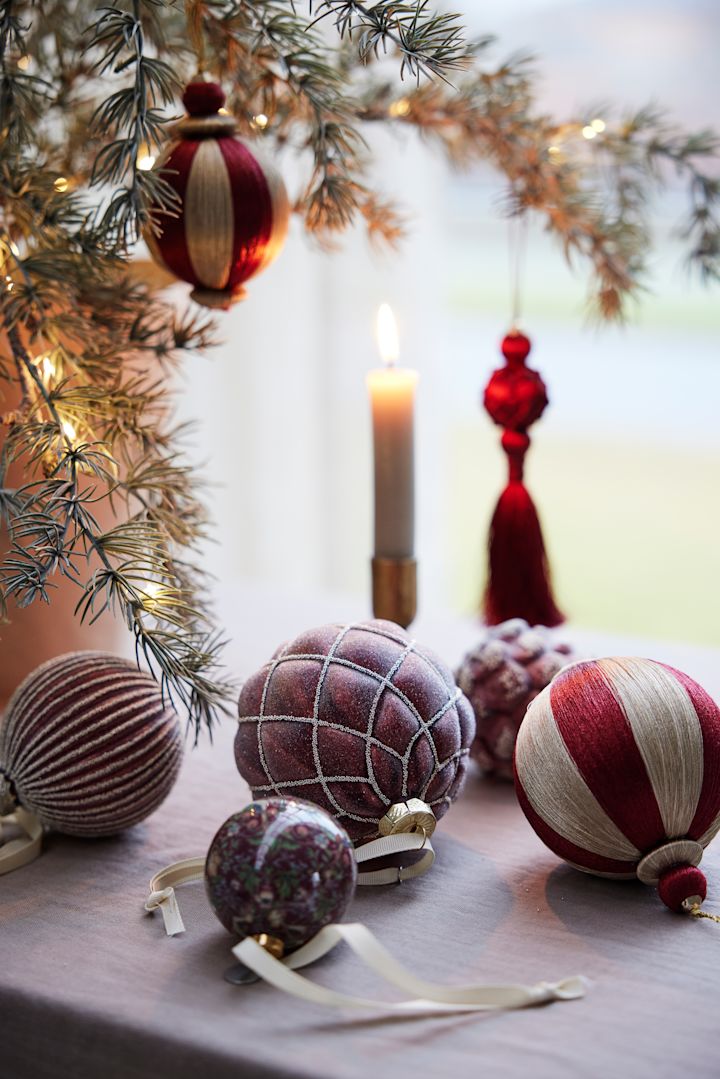 Verschillende kerstballen van Lene Bjerre liggen als kerstdecoratie op een tafel.