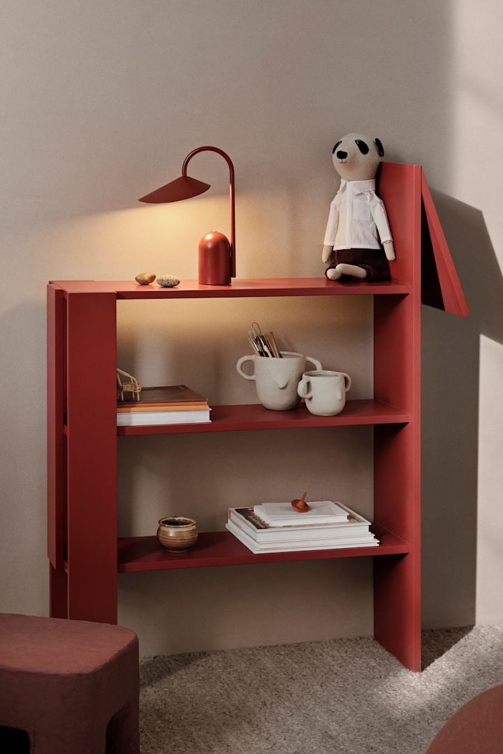Kleur in de kinderkamer brengen is een geweldig idee. Hier zie je de Giraffe boekenplank van Ferm Living in een felrode kleur, versierd met een rode draagbare lamp en wat knuffels. 