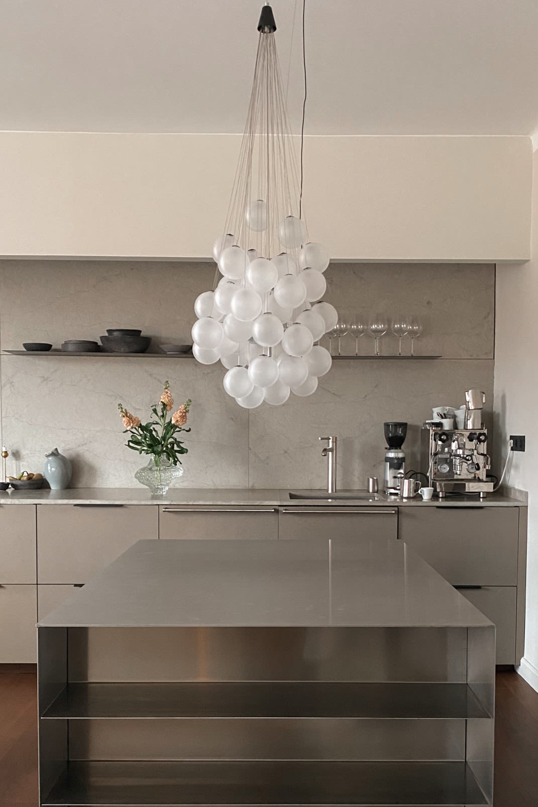 Verlevendig je huis met modern verlichtingsdesign. Hier zie je de Stochastic plafondlamp van Luce Plan, een verzameling glazen bollen die in een groep boven een roestvrijstalen werktafel hangen. 