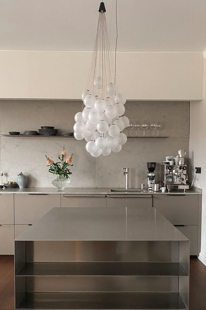 Verlevendig je huis met modern verlichtingsdesign. Hier zie je de Stochastic plafondlamp van Luce Plan, een verzameling glazen bollen die in een groep boven een roestvrijstalen werktafel hangen. 