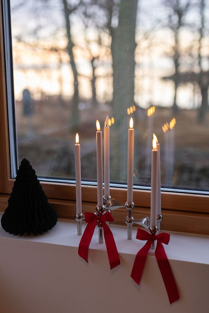 Strikken zijn een trend in de kerstdecoratie van 2025. Bind er een paar rond de stoffen kandelaar en zet die op de vensterbank.