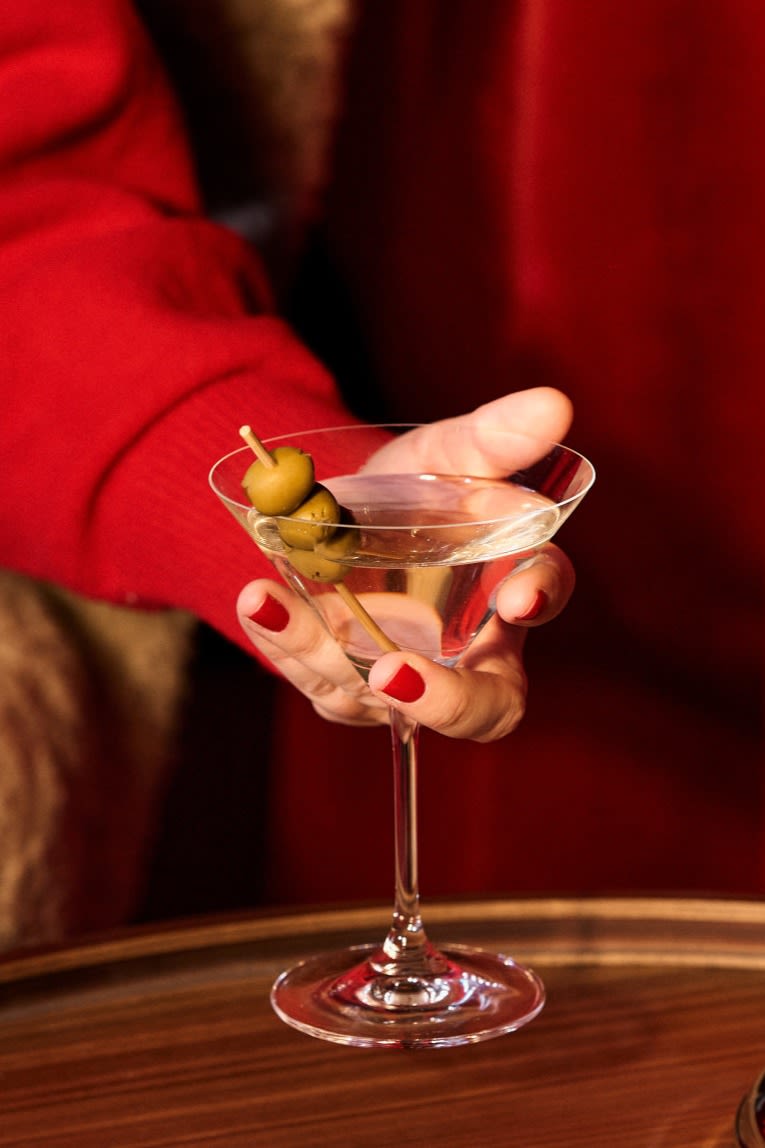 Verschillende soorten cocktailglazen: Welk glas voor welke cocktail? Hier zie je een hand die het perfecte glas vasthoudt voor martini's met olijven.
