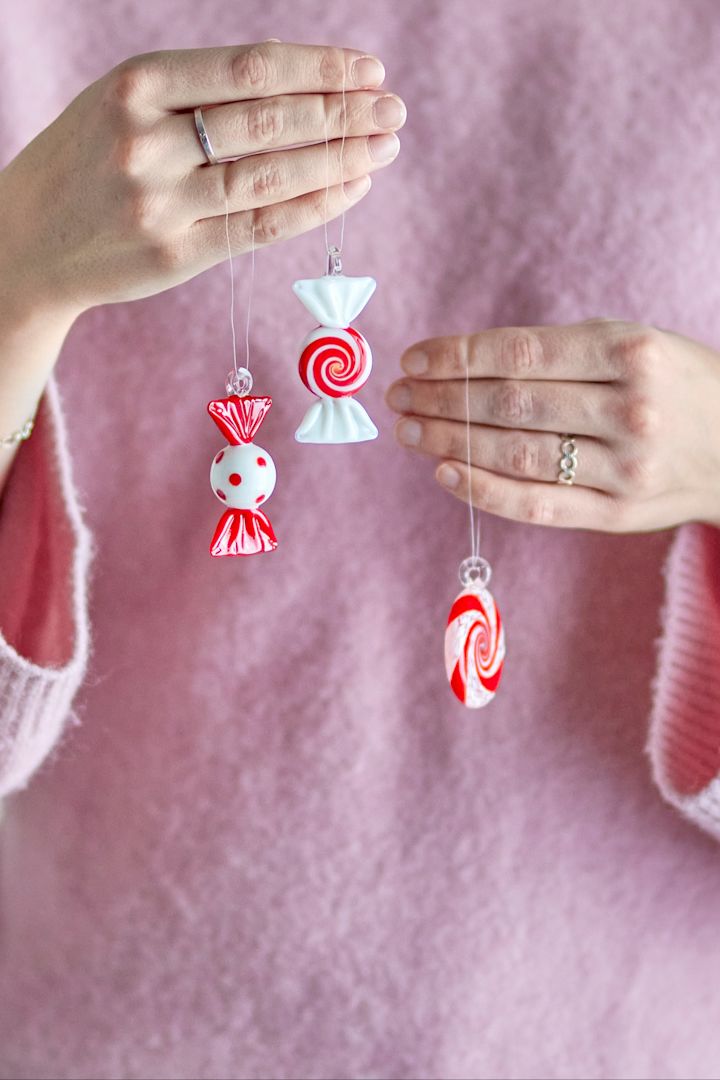 Kerstdecoratie 2025: Een vrouw houdt de drie feestelijke decoratiehangers van Bloomingville in de vorm van snoepjes omhoog naar de camera.