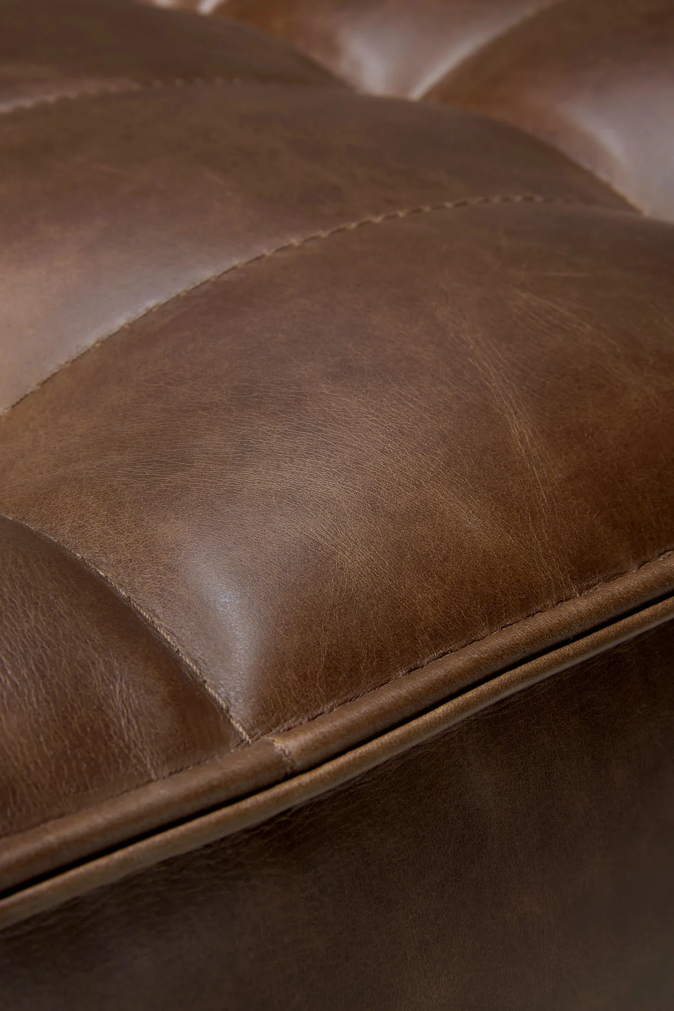 Close-up van bruin, getextureerd leer met gewatteerde stiksels.