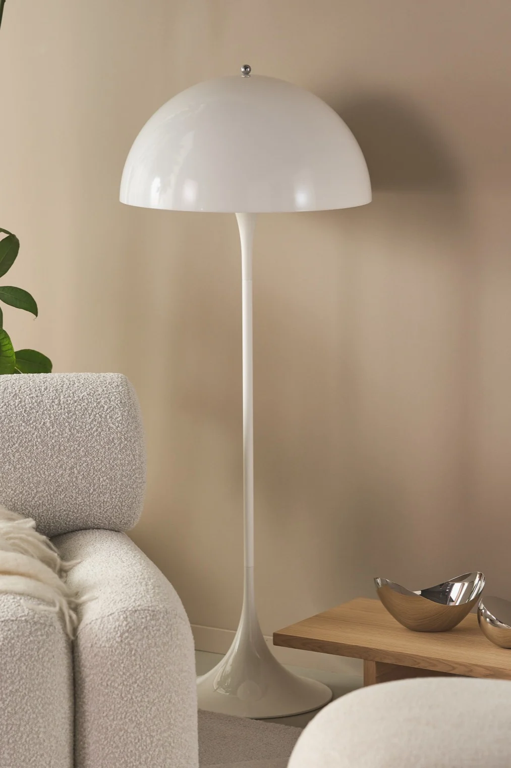 Verlevendig je huis met moderne vloerlampen - hier zie je de Panthella vloerlamp in een beige woonkamer met groene planten en opvallende meubels. 