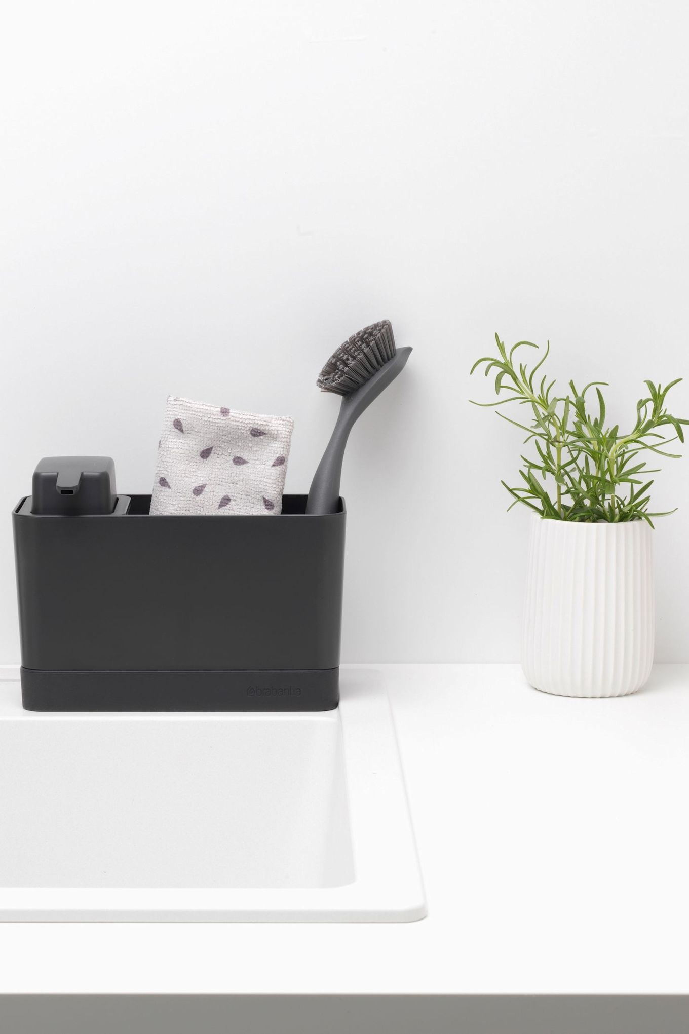 Maak je koekenpan schoon met de Brabantia gootsteenorganiser, die een zeepdispenser, vaatdoek en afwasborstel bevat.