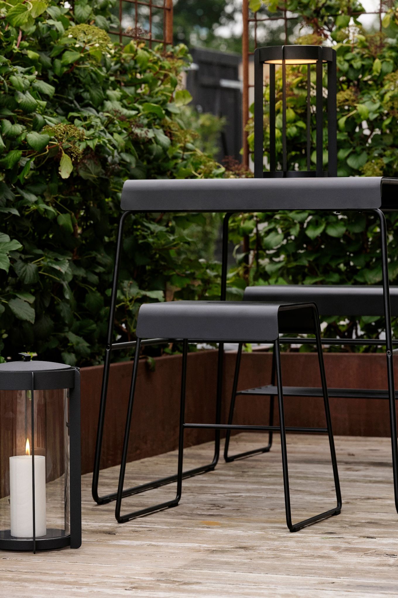 De tafel en kruk uit de outdoor collectie van Zone Denmark staan buiten op een terras.