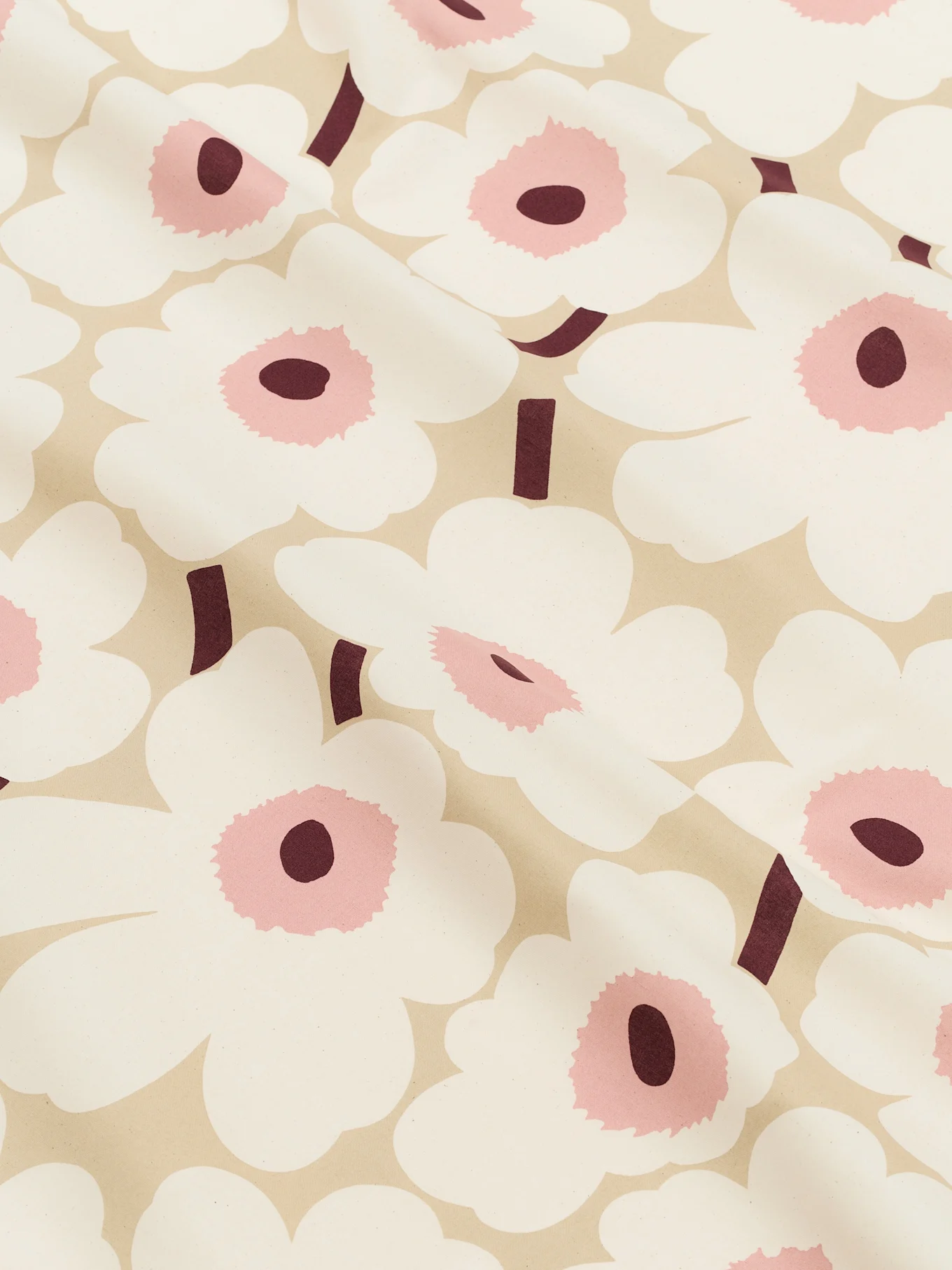 Close-up van een lichtbeige stof met een patroon van grote witte gestileerde bloemen met roze centra en donker bordeauxrode stelen.
