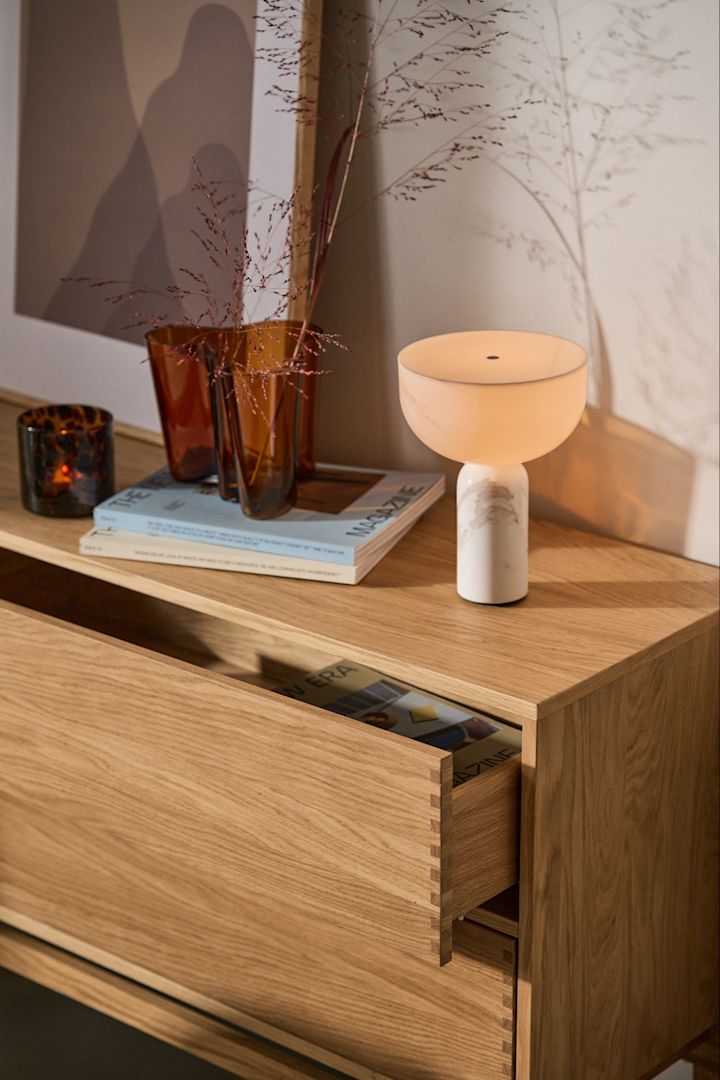 Verlevendig je huis met moderne lampen. Hier zie je de draagbare Kizu lamp van New Works op een houten dressoir.