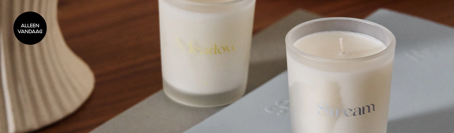 Twee matte witte kaarsen, één gelabeld 'Meadow' in goud en één 'Stream' in zilver, met een 'TODAY ONLY'-tag.