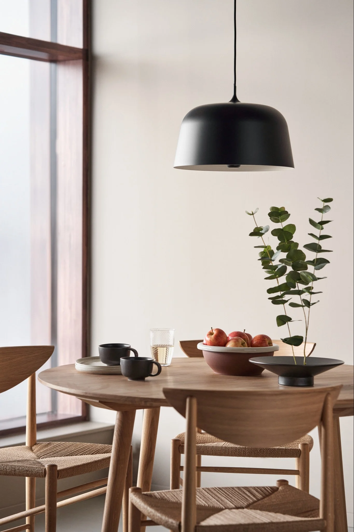 Moderne lampen geven je huis snel een stijlvolle uitstraling. Hier zie je de Halo plafondlamp van Scandi Living in de kleur zwart boven een ronde eettafel hangen.  