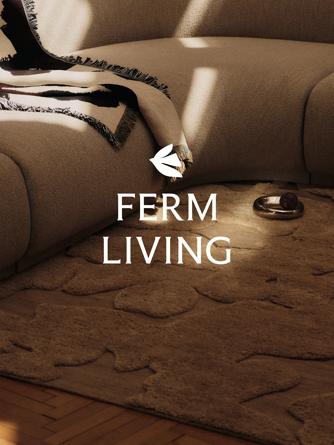 Een gezellige scène met een lichtbruine gestructureerde bank, een gedessineerde deken, een bruin vloerkleed met organische vormen en een decoratieve schaal.