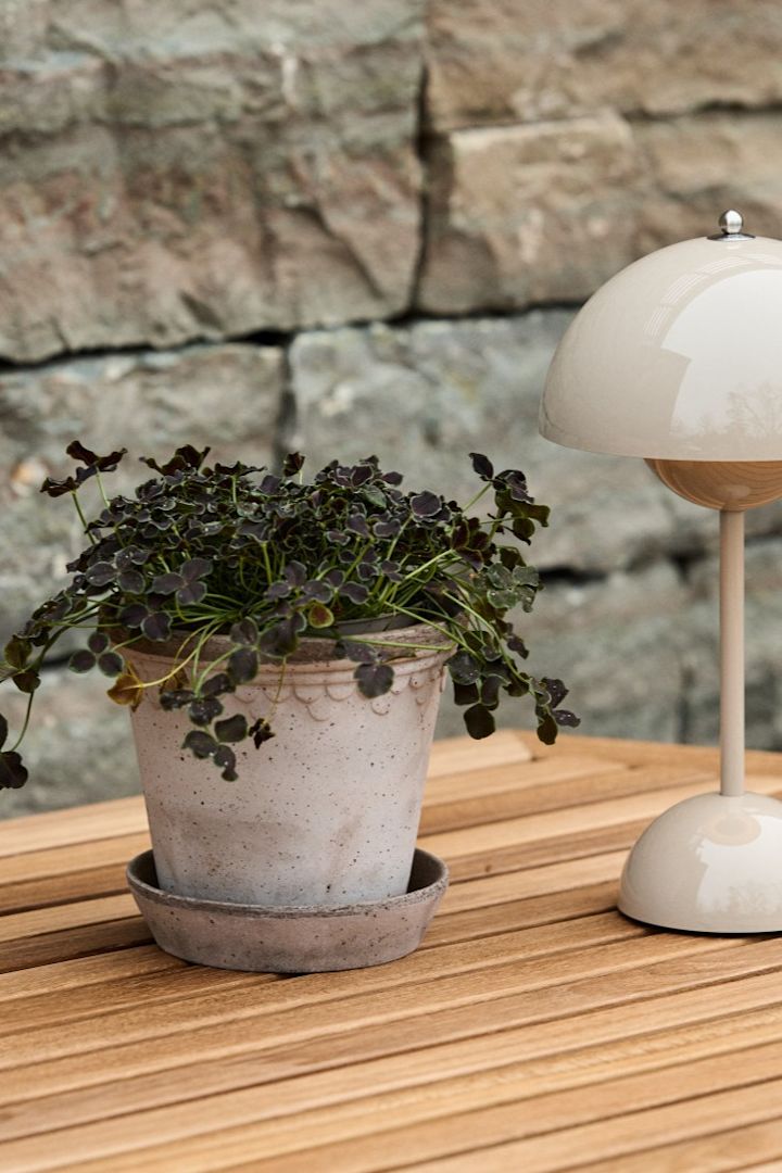 De Kopenhagen buitenpot staat op een houten eettafel met de draagbare Flowerpot VP9 tafellamp.