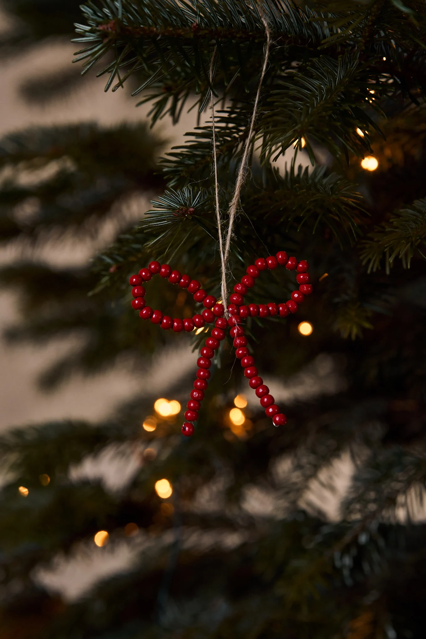 Kerstkrans met een grote rode fluwelen strik op een verweerde rode houten deur met bevroren dennentakken.