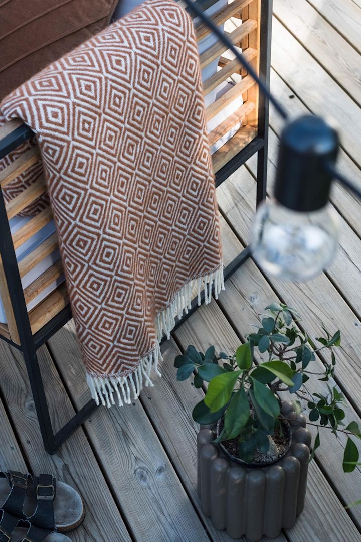 De bruine Mist bloempot van DBKD staat op het terras naast een bankje met een deken in het huis van @lindaz.se.