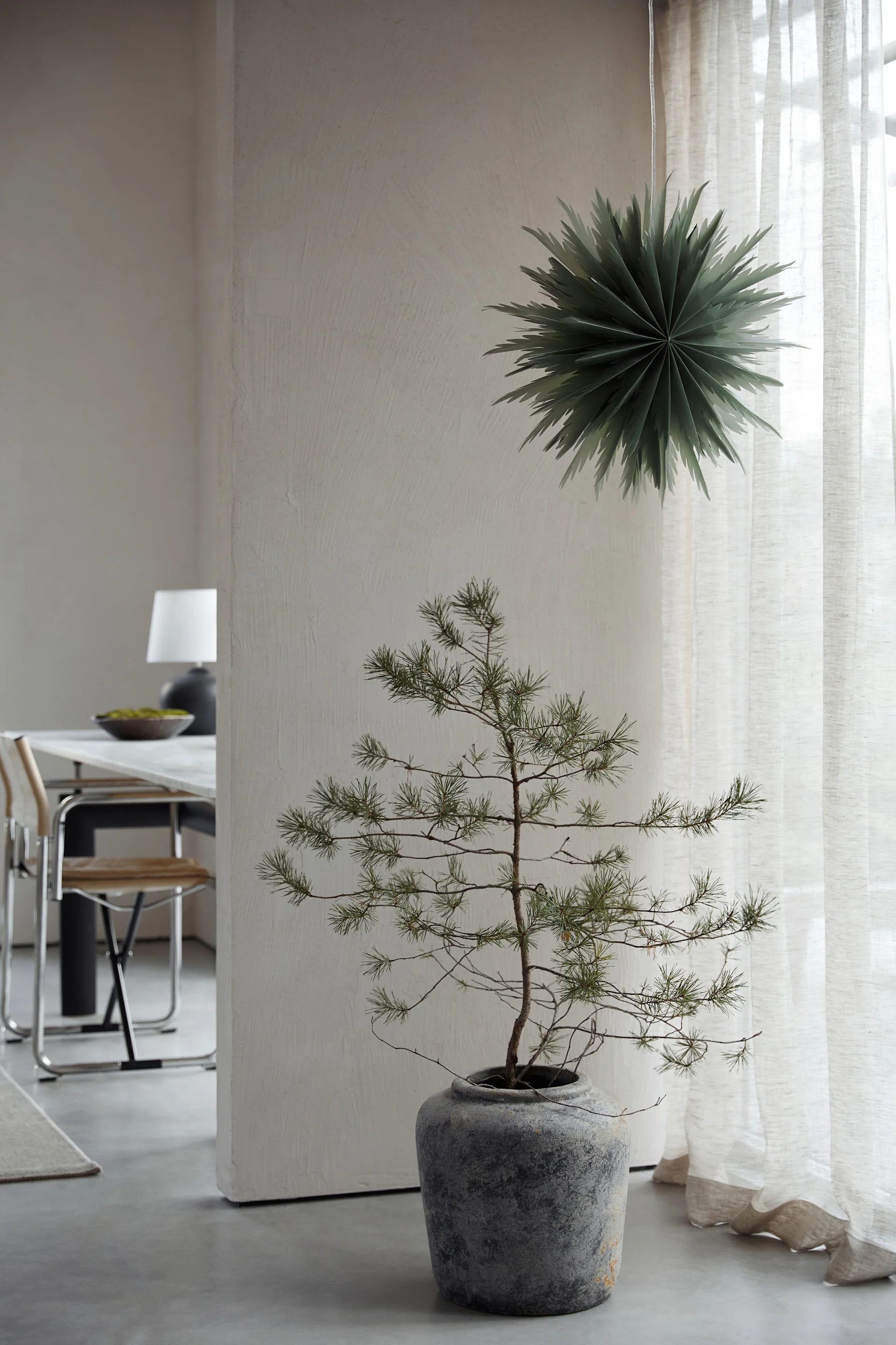 Minimalistische kerstdecoratie zoals de papieren kerstster Oslo van Watt & Veke. Hier te zien hangend in het raam van een neutraal gekleurde woonkamer.