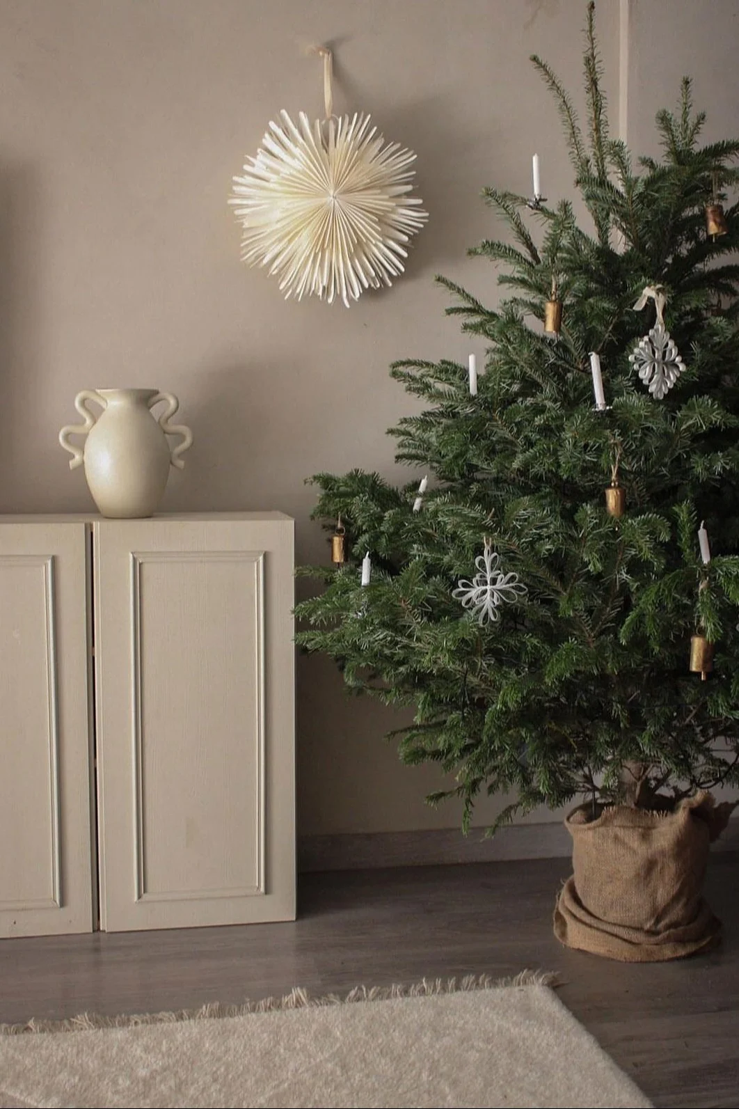 Minimalistische kerstdecoratie zoals de papieren kerstster Oslo van Watt & Veke. Hier te zien hangend in het raam van een neutraal gekleurde woonkamer.