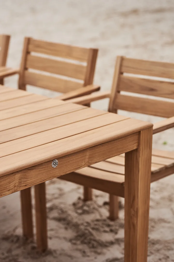 Houten tuintafel met stoelen op zand, met een '188'-plaatje.