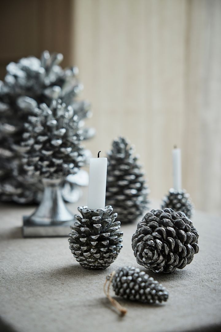 Meerdere zilverkleurige dennenappels van Lene Bjerre liggen op een tafel en zijn de perfecte kerstdecoratie voor 2025.