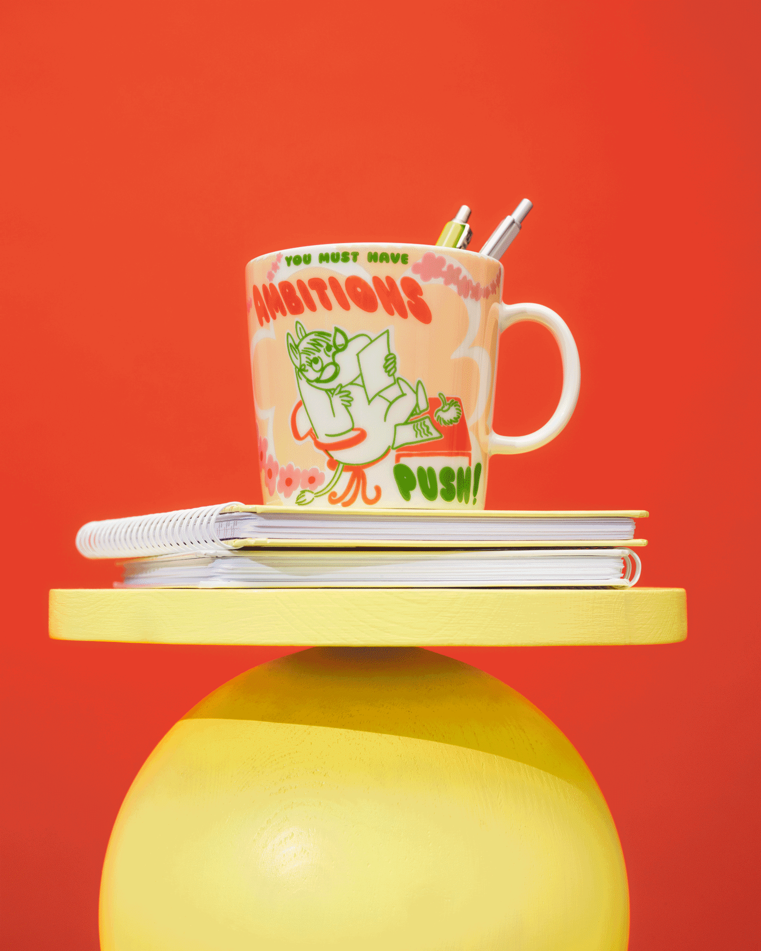 Vier kleurrijke Moomin-mokken op gele en rode gelaagde displays tegen een rode achtergrond.