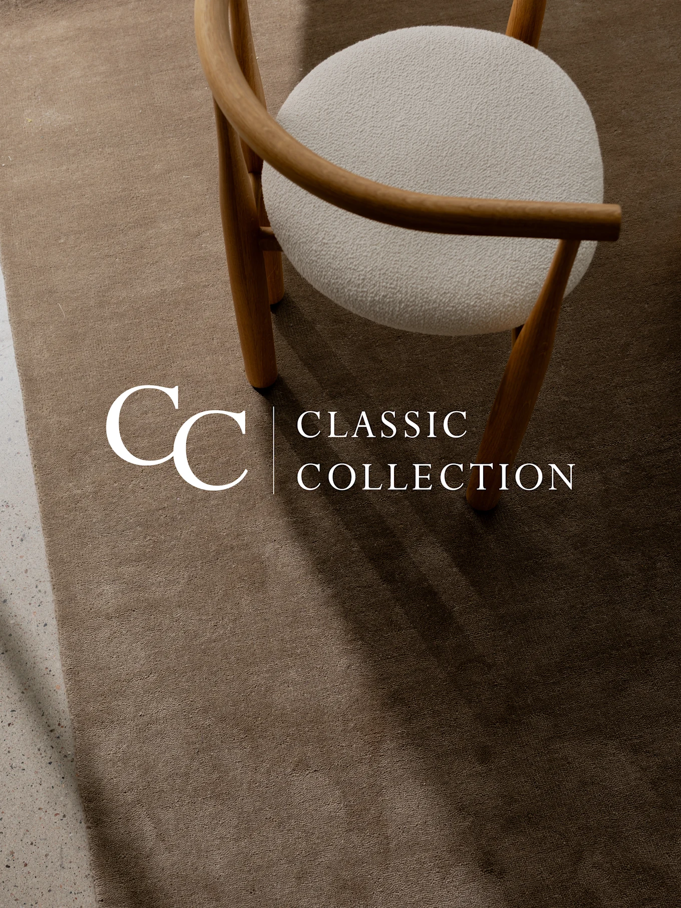 Een lichtbruin getextureerd vloerkleed met een houten stoel en een wit, pluizig zitkussen. Tekst: 'CC Classic Collection'.