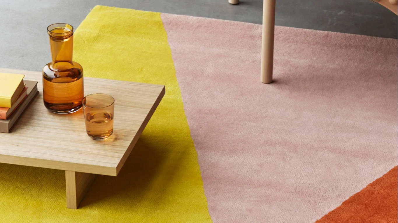 Een woonkamer ingericht met een beige vloerkleed en een groene wollen deken uit de NJRD-collectie.