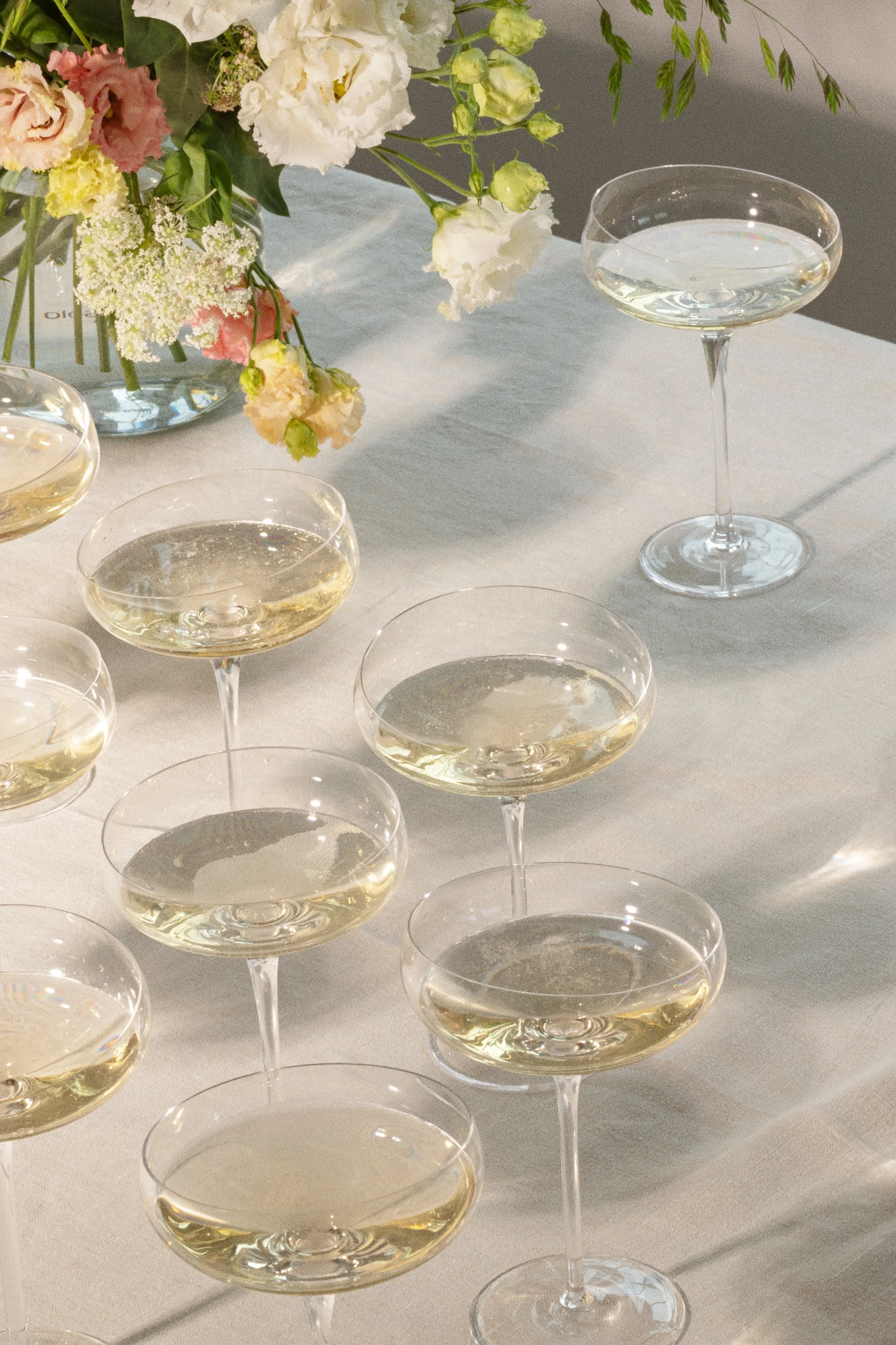 Champagneglazen met mousserende dranken op een tafel met bloemstuk.