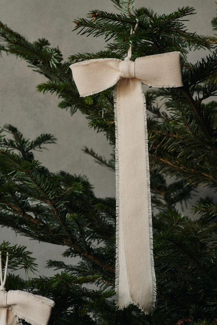 Een boogvormige decoratiehanger van Ferm Living hangt in de kerstboom.