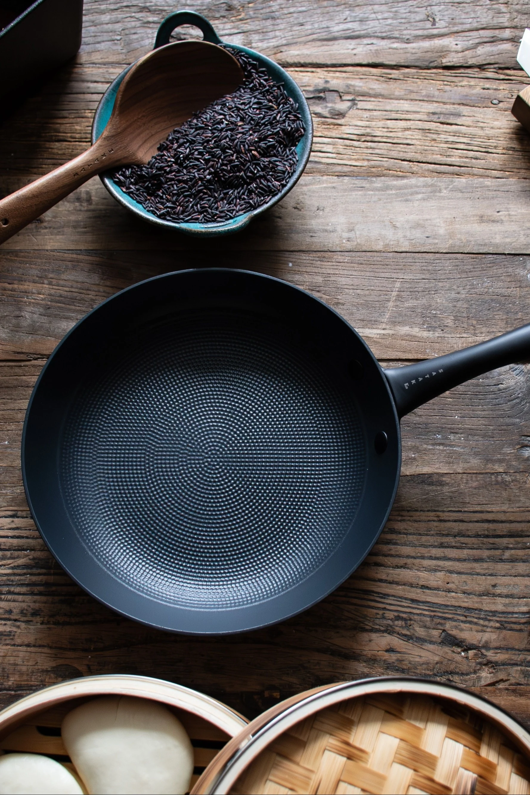 De koekenpan van Satake staat op een donkere houten tafel.