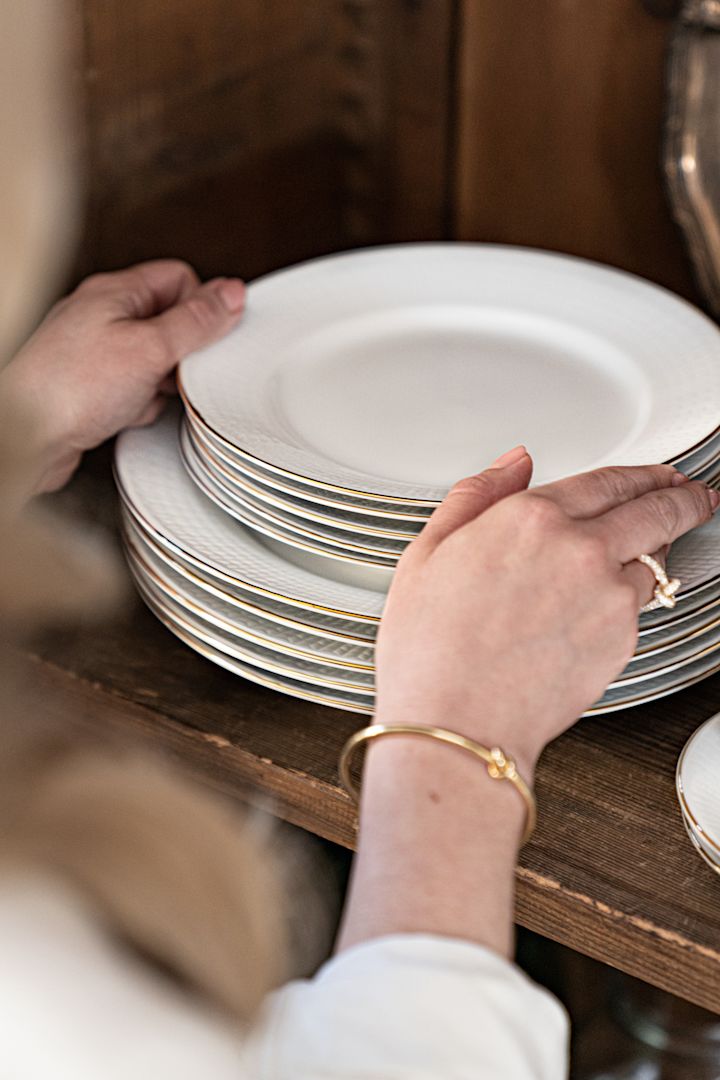 Witte borden met een gouden randje uit de Swedish Grace-serie Gala, opgestapeld in een kast. 