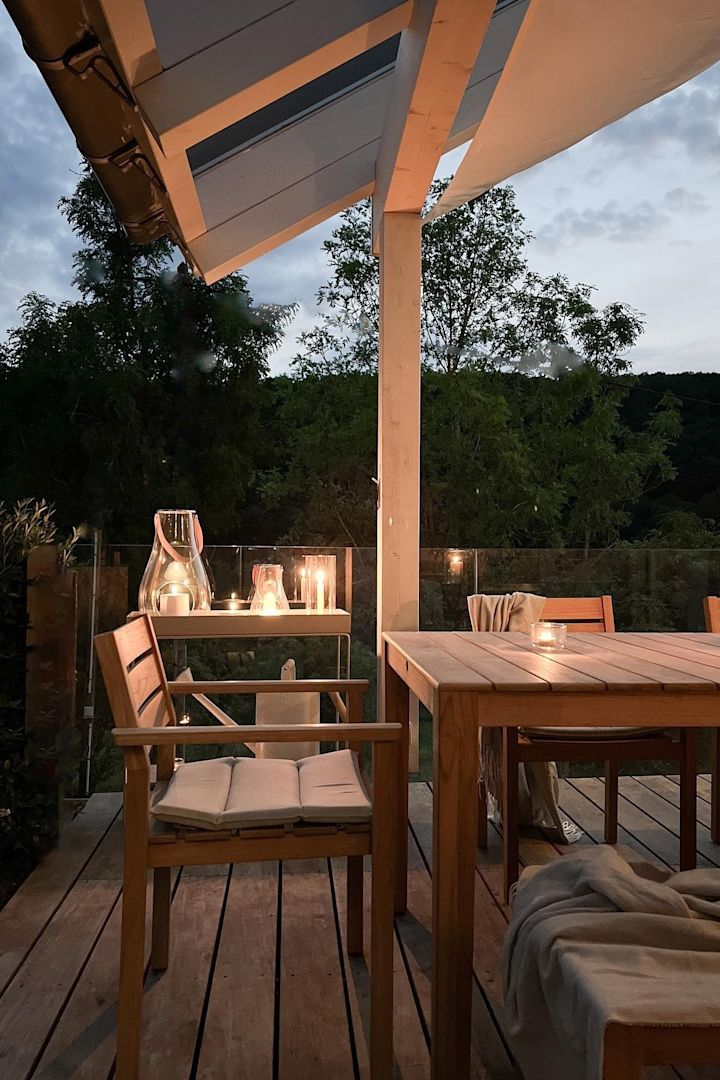Plaats verschillende lantaarns en windlichten buiten op je terras om een gezellige sfeer te creëren. Hier zie je de Design with Light lantaarn van Holmegaard op de houten terrastafel van de Duitse influencer @zuhauselig.