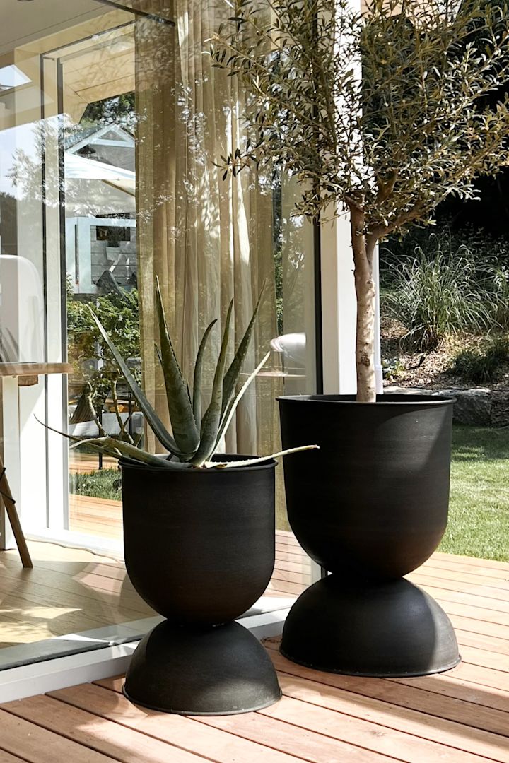 Bloempotten voor buiten: Hier zie je twee van de grote Hourglass buitenpotten van Ferm Living op een terras staan.