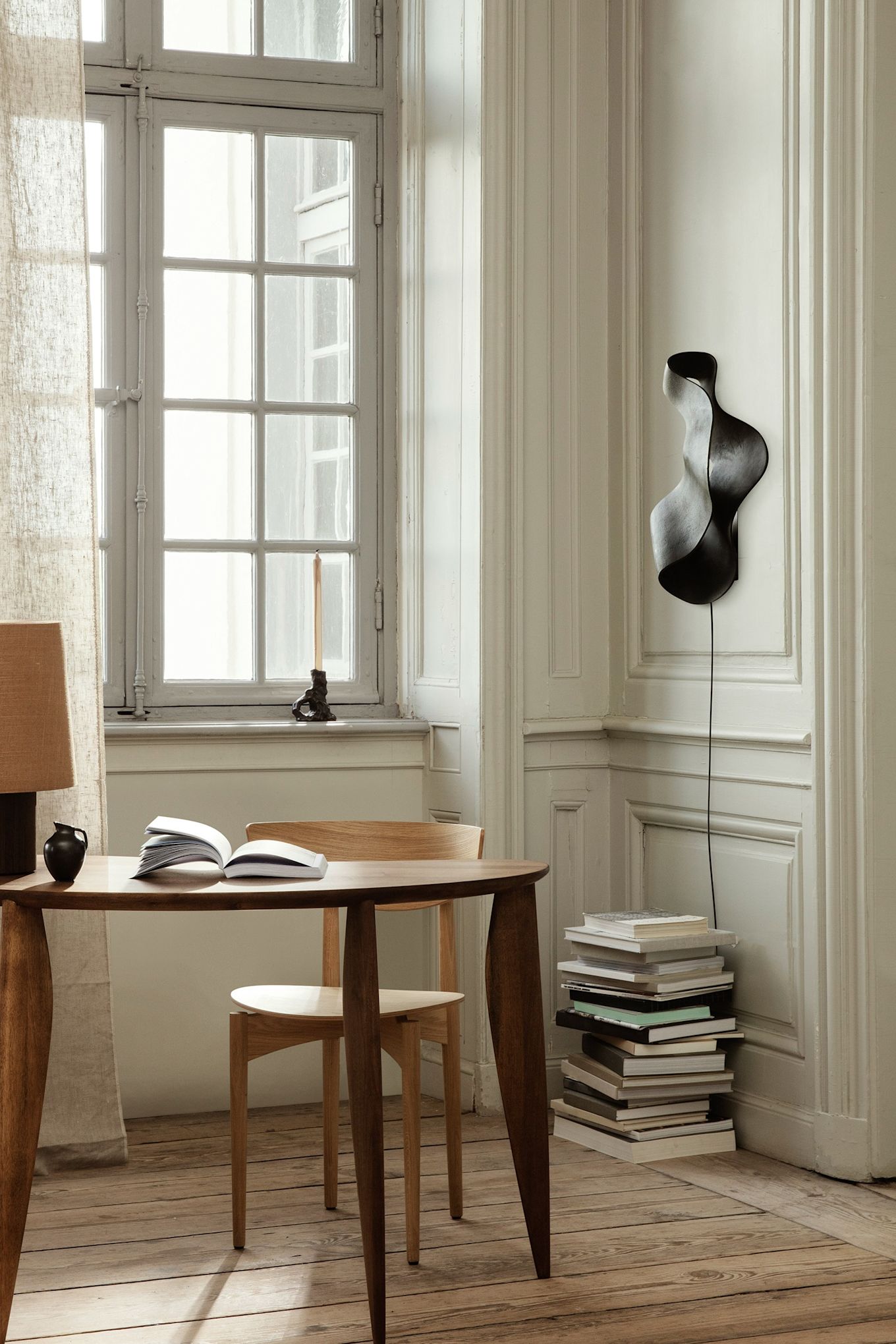 Update je huis met deze moderne verlichtingsideeën zoals de Oyster wandlamp van Ferm Living. Hier hangt hij aan de muur boven een stapel boeken. 