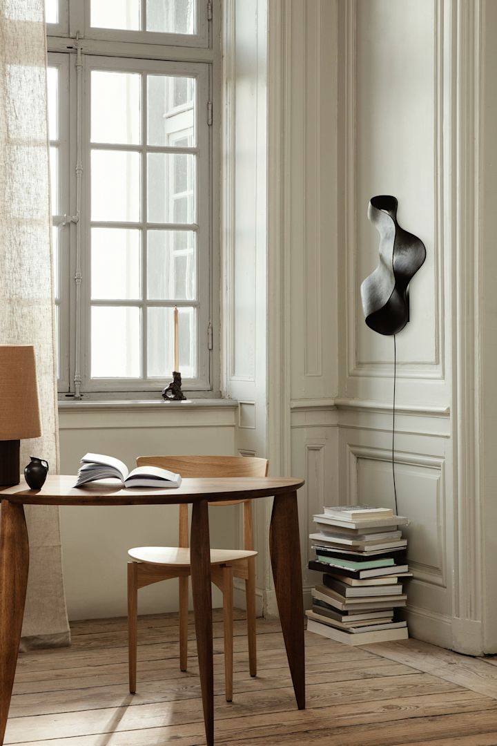 Update je huis met deze moderne verlichtingsideeën zoals de Oyster wandlamp van Ferm Living. Hier hangt hij aan de muur boven een stapel boeken. 