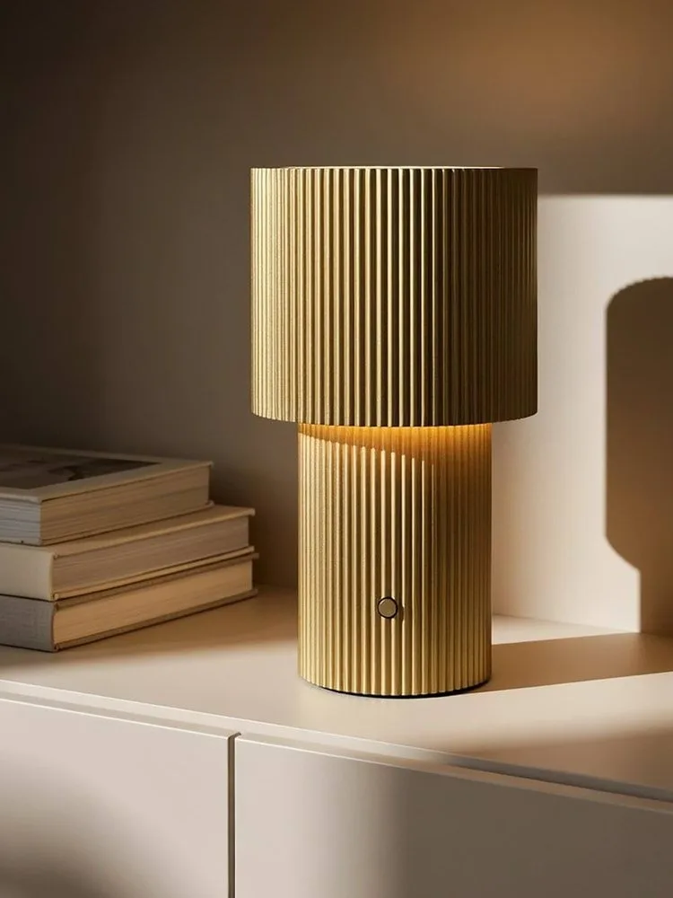 Gouden geribbelde tafellamp, gloeiend, met een ronde knop op de voet.