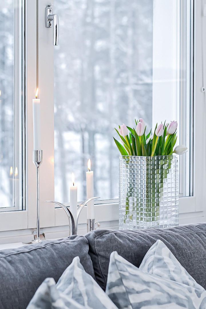 Versier je vensterbank met kaarsen of mooie bloemen, vooral in de donkere maanden. Hier zie je verse tulpen in de City Hurricane vaas van Louise Roe, naast verschillende zilveren kandelaars met witte kaarsen erin op de vensterbank door @josefinsinredning.