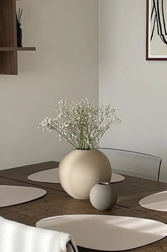 De Ball vaas in de kleur zand en grijs in twee verschillende maten staat op een eettafel. 