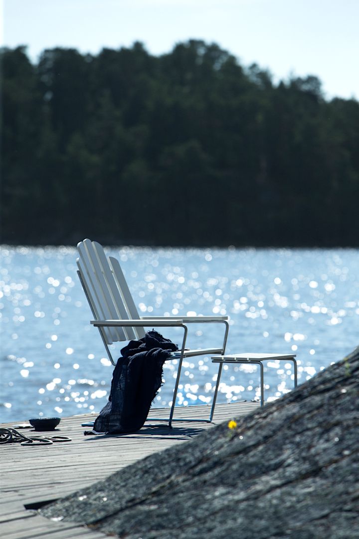 Maak kennis met Grythyttan Stålmöbler, hier een witte fauteuil aan zee.