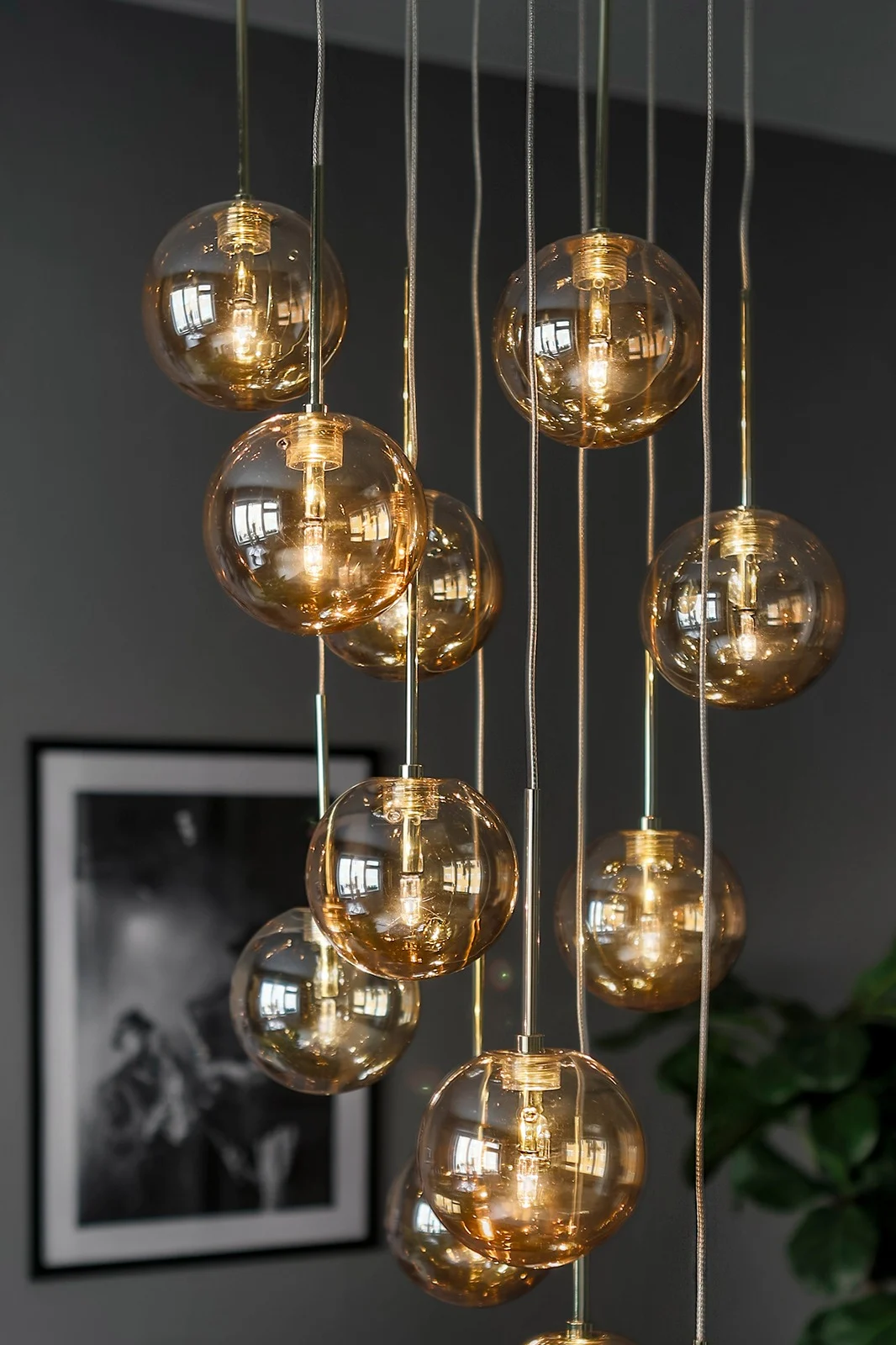 Moderne multi-pendellamp met verlichte amberkleurige glazen bollen die op verschillende hoogtes hangen.